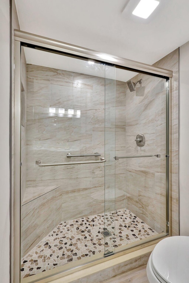 bathroom featuring toilet and a shower with shower door