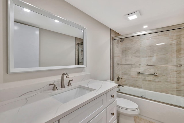 full bathroom featuring combined bath / shower with glass door, vanity, and toilet