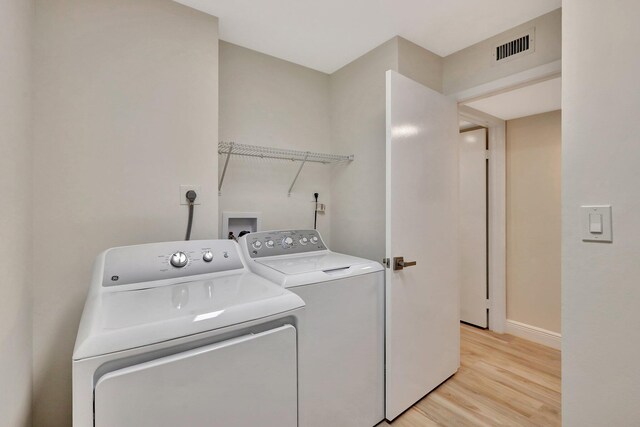 laundry area with washer and clothes dryer and light hardwood / wood-style flooring