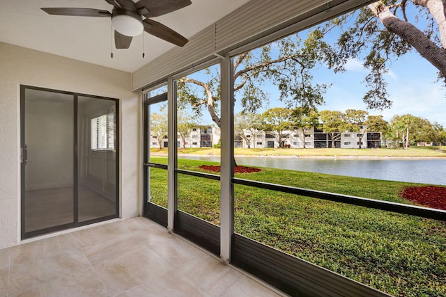 unfurnished sunroom featuring ceiling fan and a water view