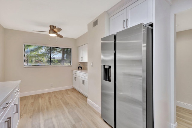 kitchen with white cabinets, ceiling fan, stainless steel fridge, and light hardwood / wood-style floors