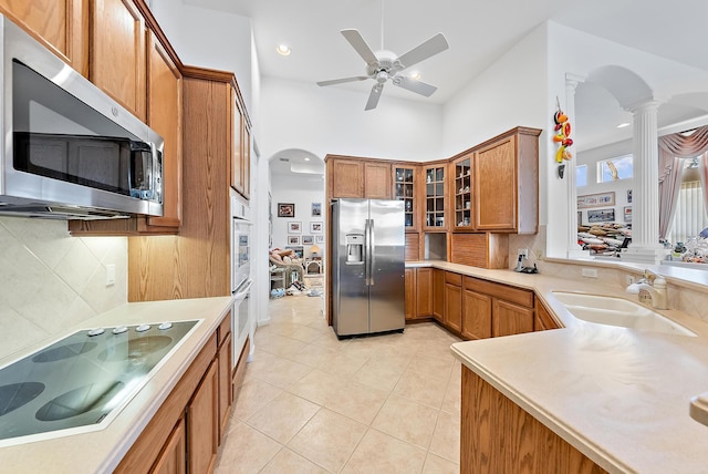 kitchen with ornate columns, sink, stainless steel appliances, backsplash, and light tile patterned flooring