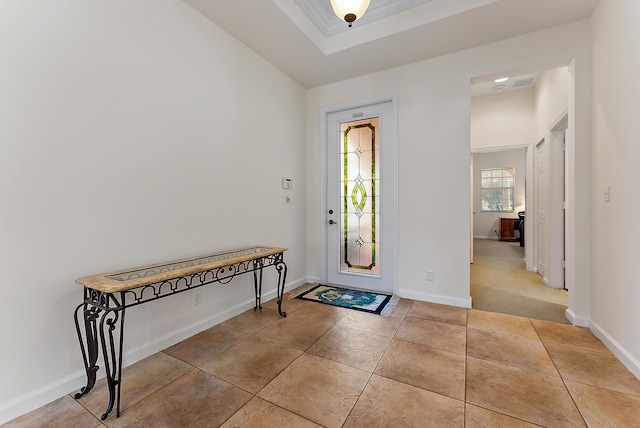 tiled entrance foyer featuring a tray ceiling