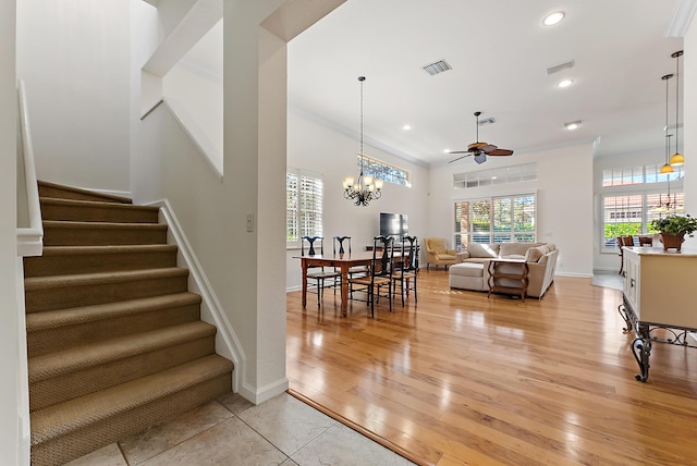 stairway featuring crown molding, wood-type flooring, and ceiling fan with notable chandelier