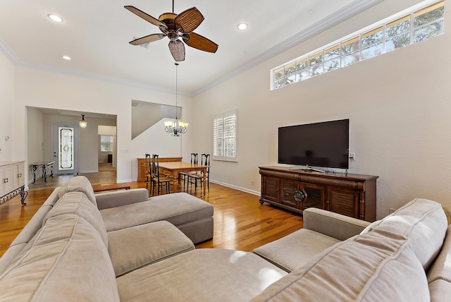 living room featuring crown molding, ceiling fan with notable chandelier, and light wood-type flooring