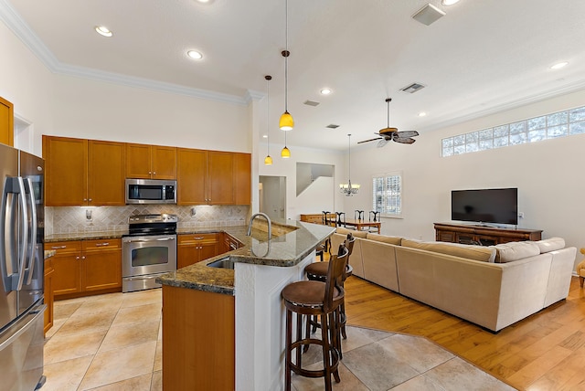 kitchen with appliances with stainless steel finishes, a breakfast bar, pendant lighting, sink, and kitchen peninsula