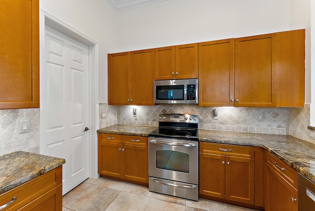 kitchen featuring tasteful backsplash, appliances with stainless steel finishes, light tile patterned flooring, and dark stone countertops