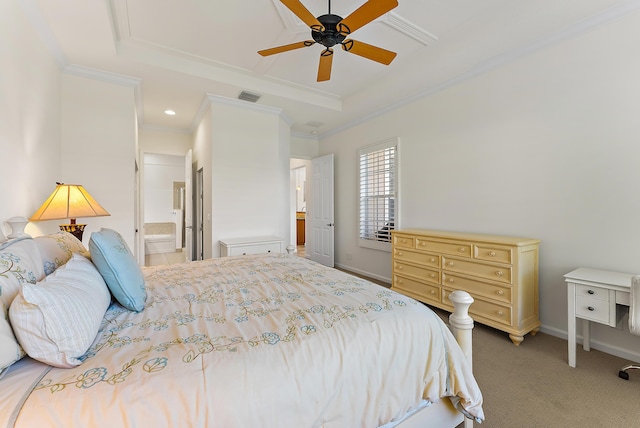 carpeted bedroom with a raised ceiling, crown molding, and ensuite bath