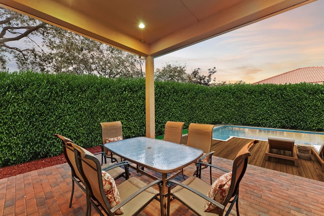 patio terrace at dusk featuring a fenced in pool