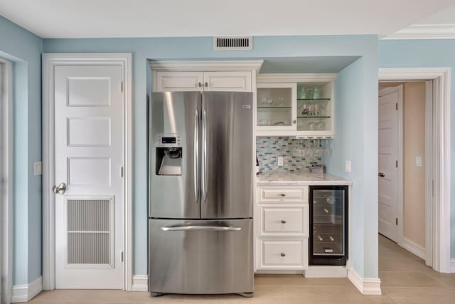 kitchen with white cabinets, beverage cooler, stainless steel fridge with ice dispenser, light tile patterned flooring, and light stone counters