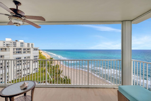 balcony with ceiling fan, a water view, and a view of the beach