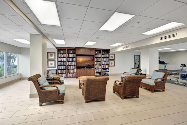 living room with a paneled ceiling and built in features