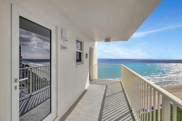 balcony with a water view and a view of the beach