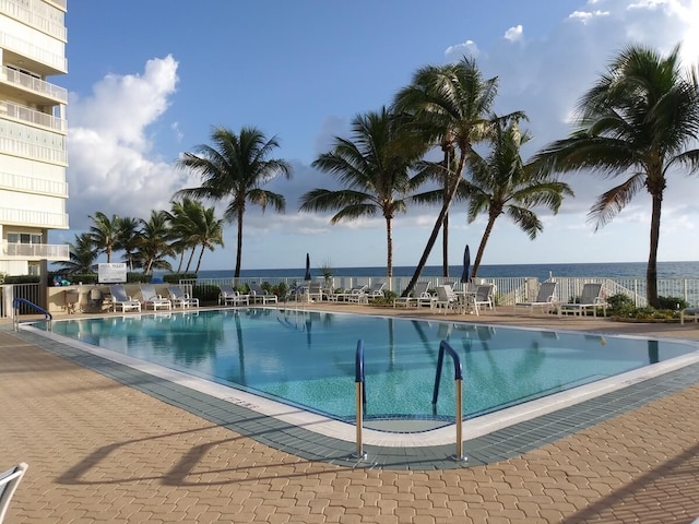 view of swimming pool with a water view and a patio area