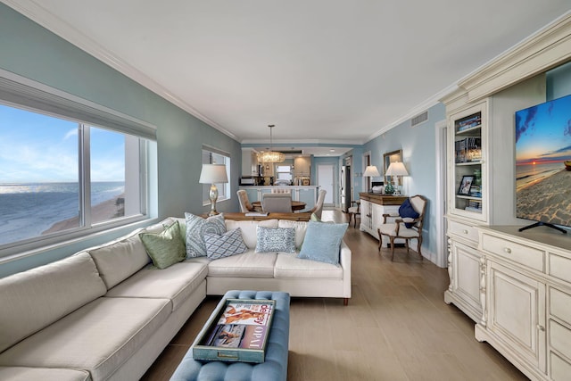 living room featuring crown molding, a water view, and light wood-type flooring