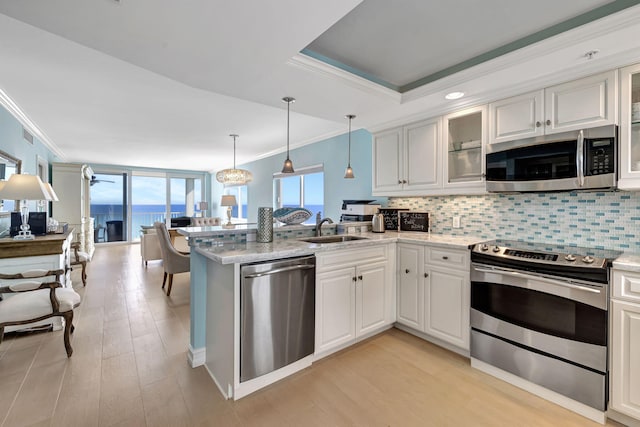 kitchen with kitchen peninsula, sink, stainless steel appliances, and white cabinetry