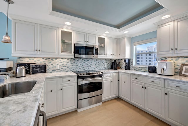 kitchen with stainless steel appliances, white cabinets, and hanging light fixtures