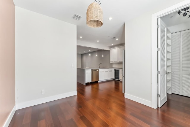 unfurnished living room featuring sink, beverage cooler, and dark wood-type flooring