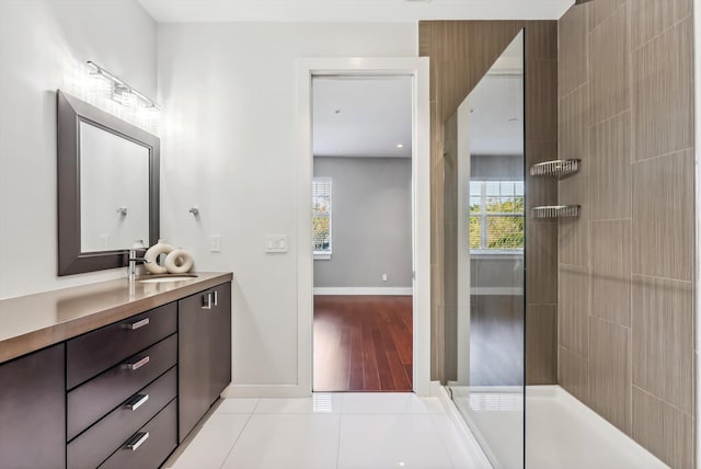 bathroom featuring tile patterned flooring, a tile shower, and vanity