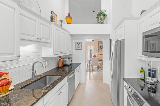 kitchen with white cabinetry, sink, tasteful backsplash, dark stone countertops, and appliances with stainless steel finishes