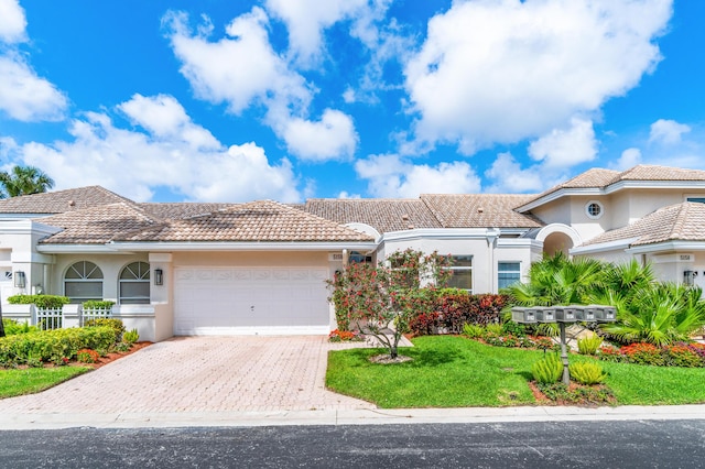 mediterranean / spanish home featuring a front yard and a garage