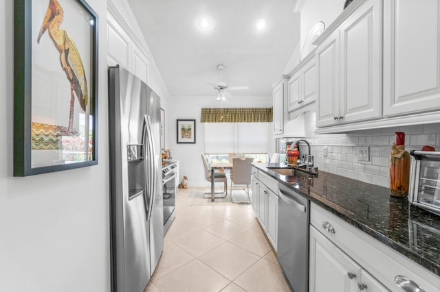 kitchen featuring backsplash, sink, light tile patterned floors, white cabinetry, and stainless steel appliances