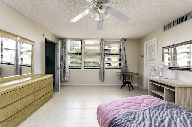 bedroom with ceiling fan, light tile patterned floors, and a textured ceiling