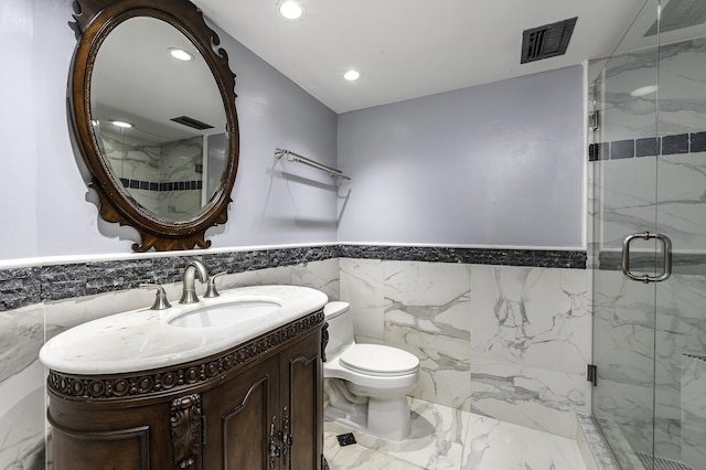 bathroom with vanity, toilet, tile walls, and a shower with shower door