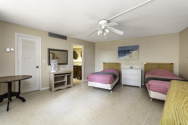 tiled bedroom with a textured ceiling, ceiling fan, and connected bathroom