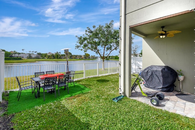 view of yard with ceiling fan and a water view