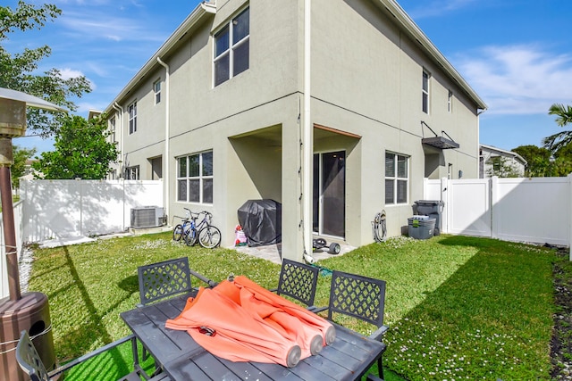 back of house featuring central AC unit and a yard