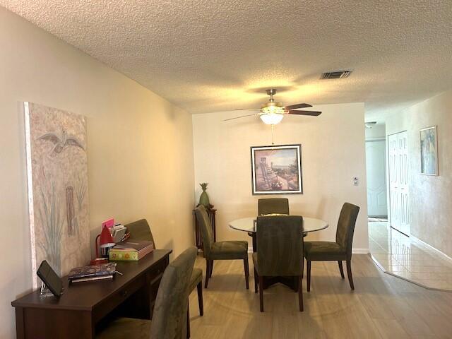 dining area featuring hardwood / wood-style flooring, ceiling fan, and a textured ceiling