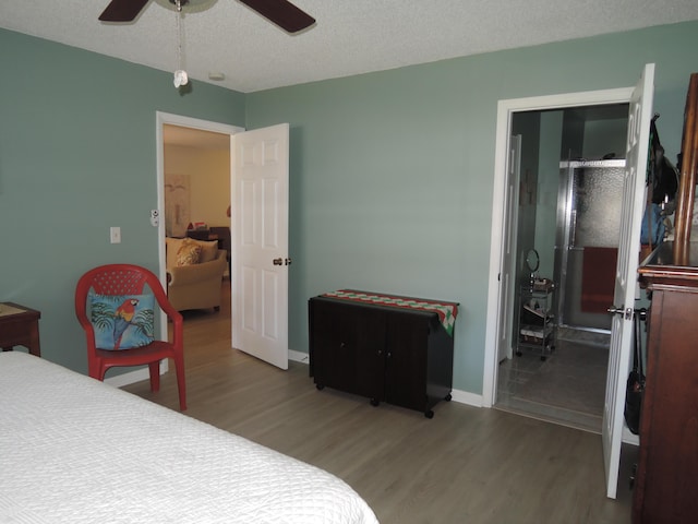 bedroom with ceiling fan, wood-type flooring, and a textured ceiling