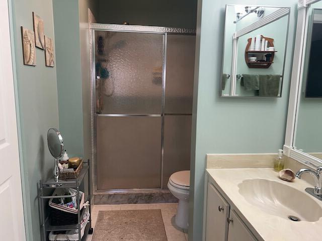 bathroom featuring tile patterned floors, vanity, toilet, and walk in shower