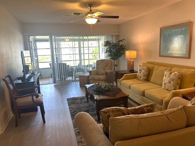 living room with hardwood / wood-style floors, a textured ceiling, and ceiling fan