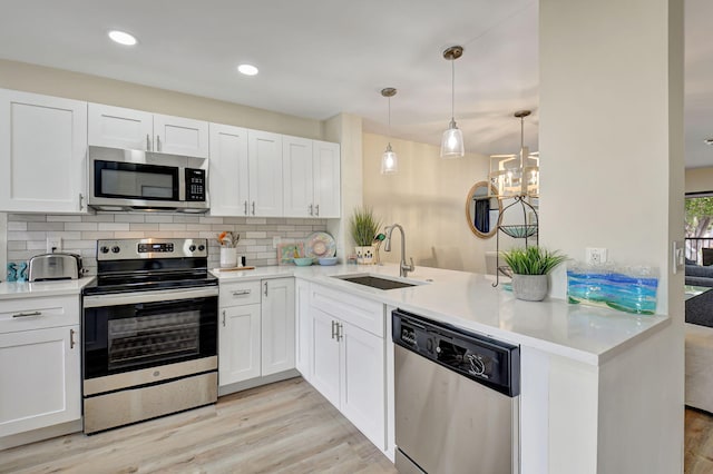 kitchen featuring stainless steel appliances, white cabinetry, sink, and kitchen peninsula