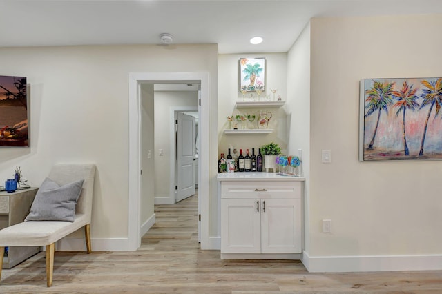 bar with white cabinetry and light wood-type flooring