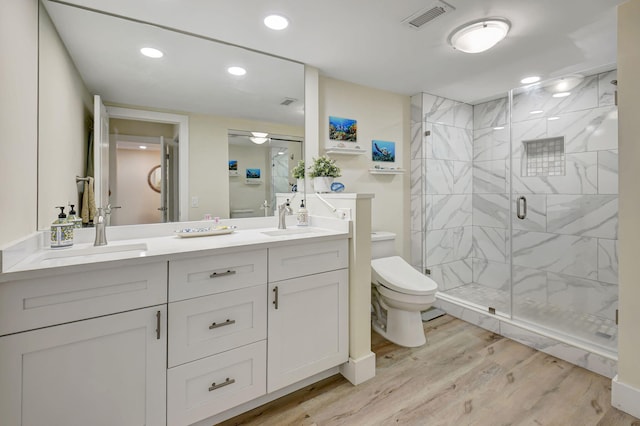 bathroom with wood-type flooring, toilet, vanity, and a shower with shower door