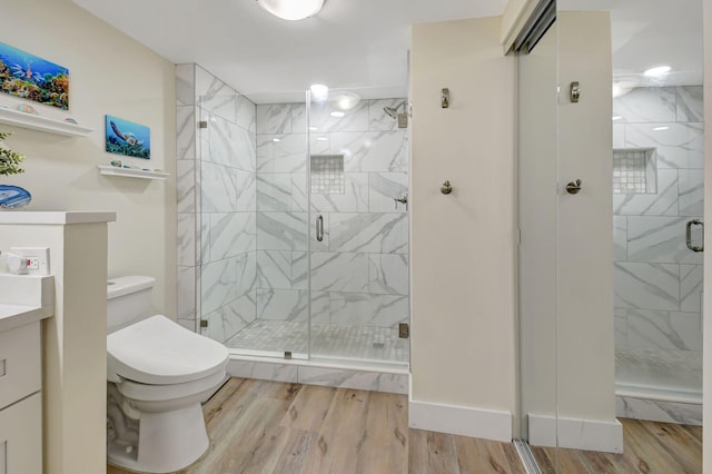 bathroom featuring vanity, toilet, a shower with shower door, and hardwood / wood-style floors