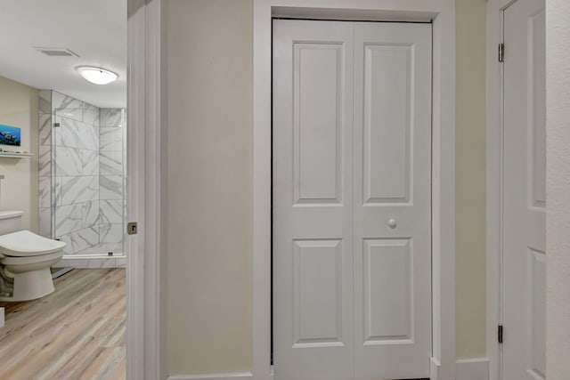 bathroom featuring an enclosed shower, wood-type flooring, and toilet