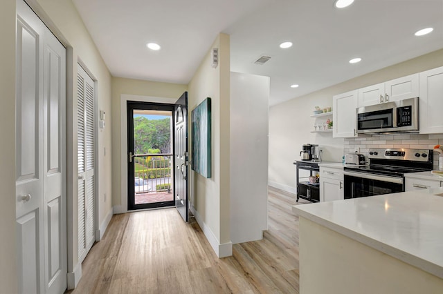 kitchen featuring tasteful backsplash, stainless steel appliances, light hardwood / wood-style floors, and white cabinets