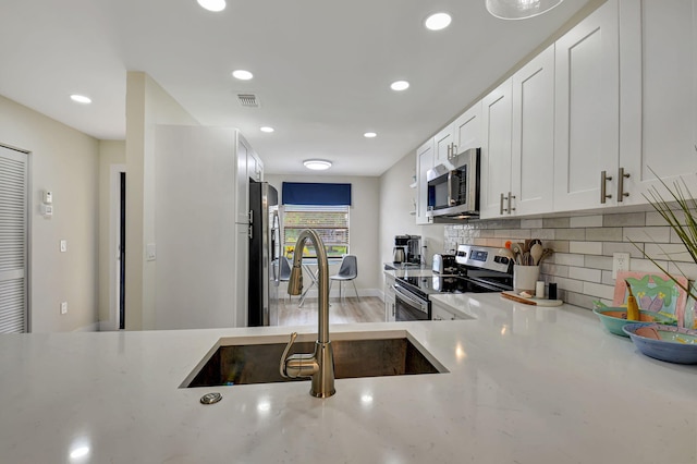 kitchen featuring stainless steel appliances, white cabinetry, sink, and tasteful backsplash