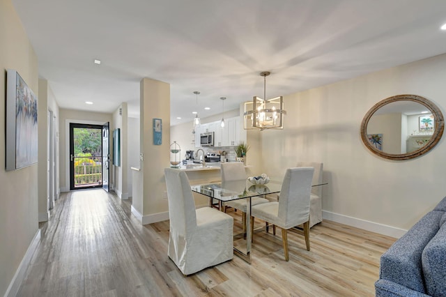 dining area with a chandelier, sink, and light wood-type flooring