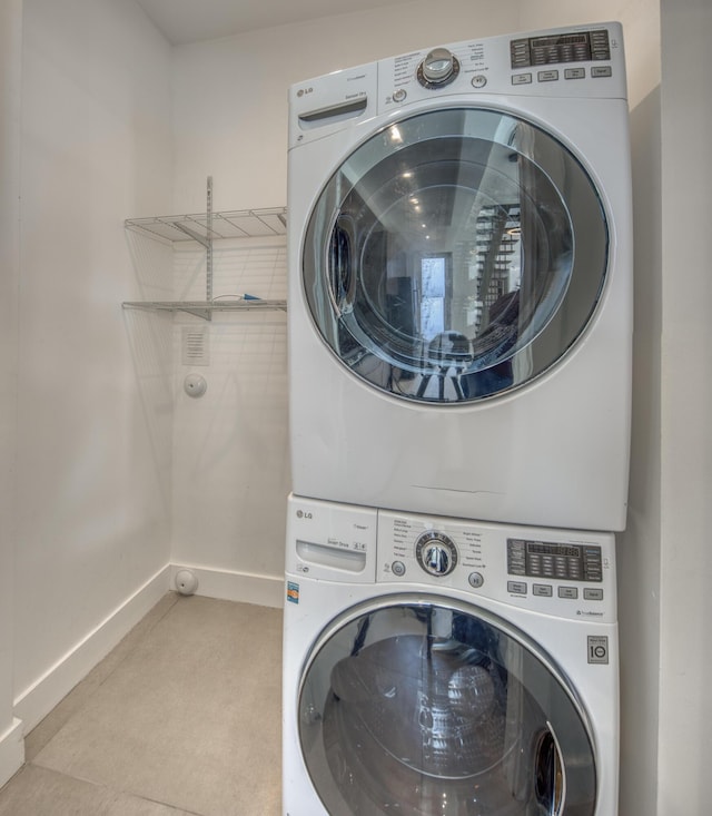 laundry room featuring stacked washer / drying machine and light tile patterned floors