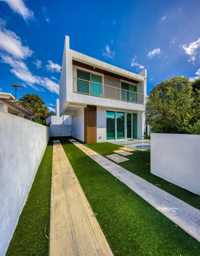 back of house featuring a balcony and a lawn