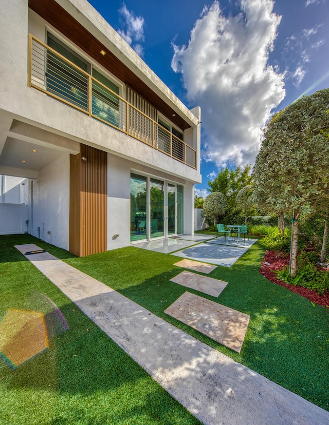 back of house featuring a lawn, a patio area, and a balcony