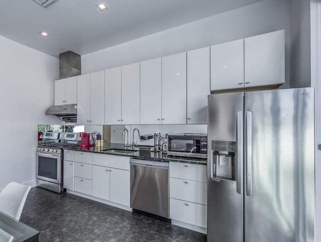 kitchen with appliances with stainless steel finishes, sink, white cabinetry, and dark stone countertops