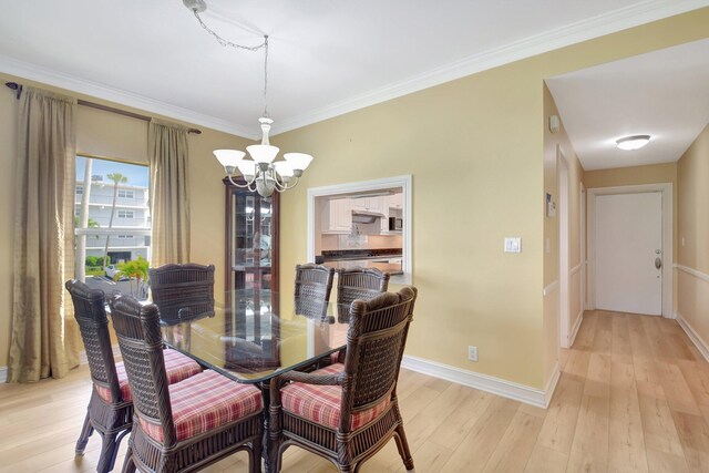 dining space with light hardwood / wood-style floors, an inviting chandelier, and crown molding