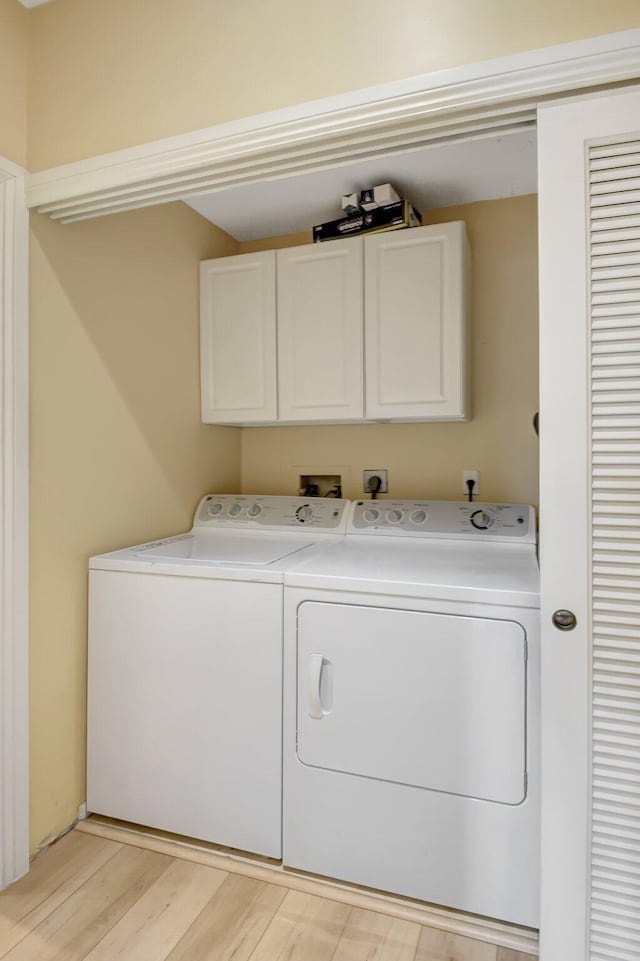 clothes washing area with cabinets, separate washer and dryer, and light hardwood / wood-style floors