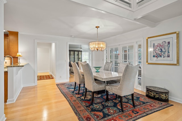 dining room with a notable chandelier, ornamental molding, and light hardwood / wood-style flooring